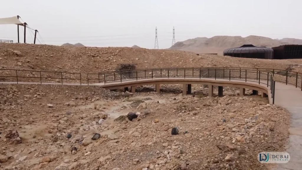 Curved boardwalk trail with railings through the rocky landscape at Buhais Geological Park