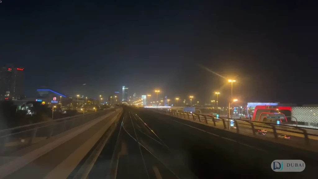 Dubai Metro tracks at night between illuminated city buildings