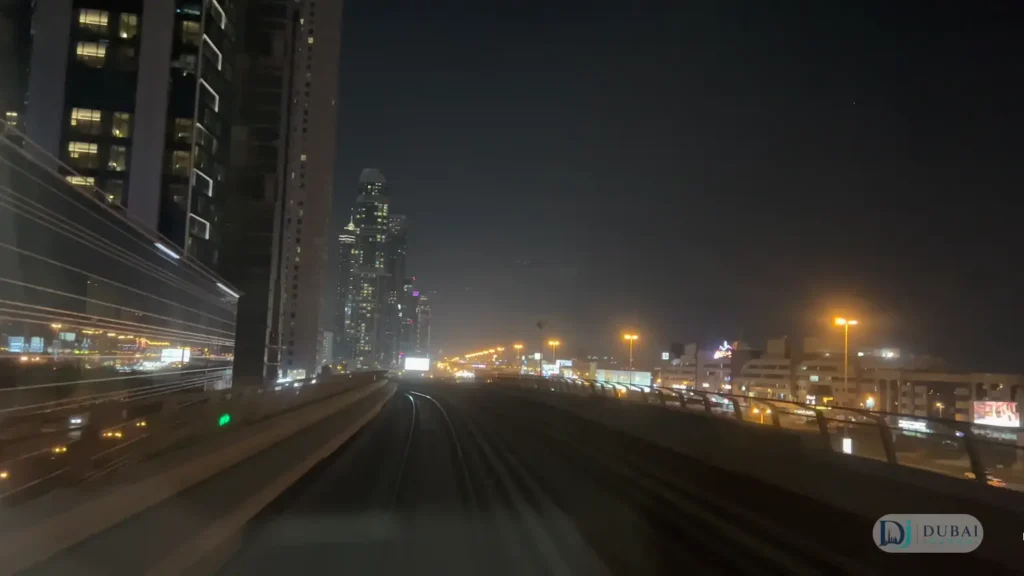 Dubai Metro tracks at night through illuminated city skyscrapers