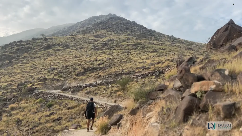 Hiker on the rocky Al Rabi trail at sunrise