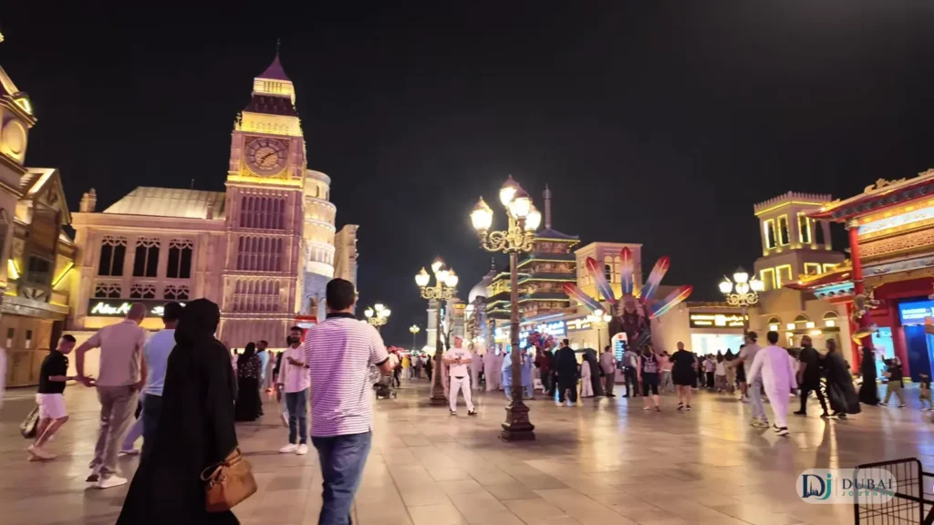 Illuminated Big Ben replica tower and walkway inside Global Village at night
