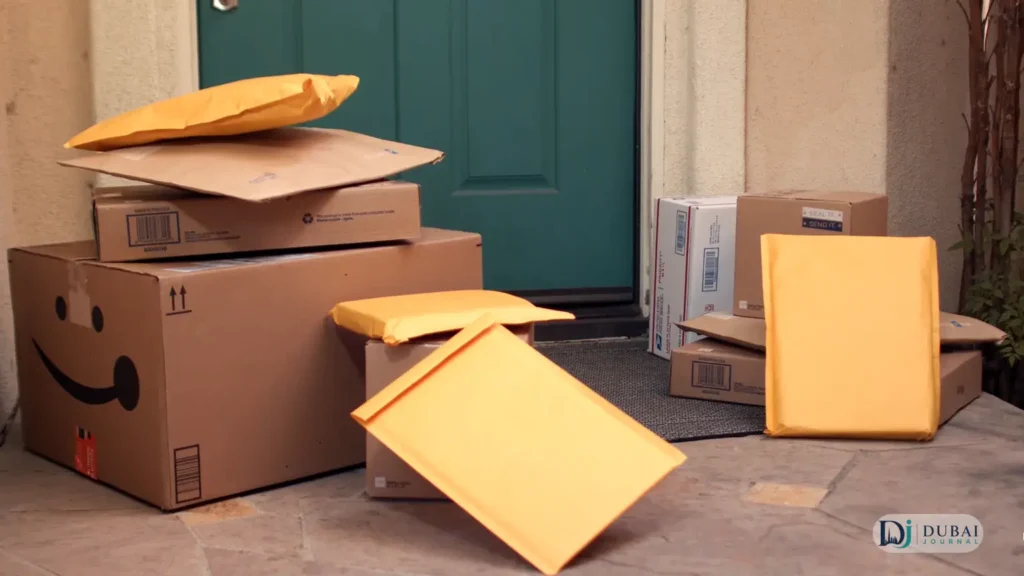 Parcels and mailers stacked at a teal doorstep